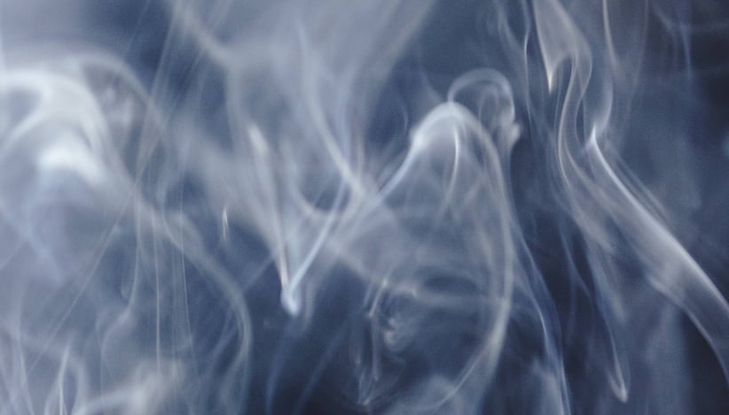 A cloud of white vapor, drifting formless against a dark blue background.